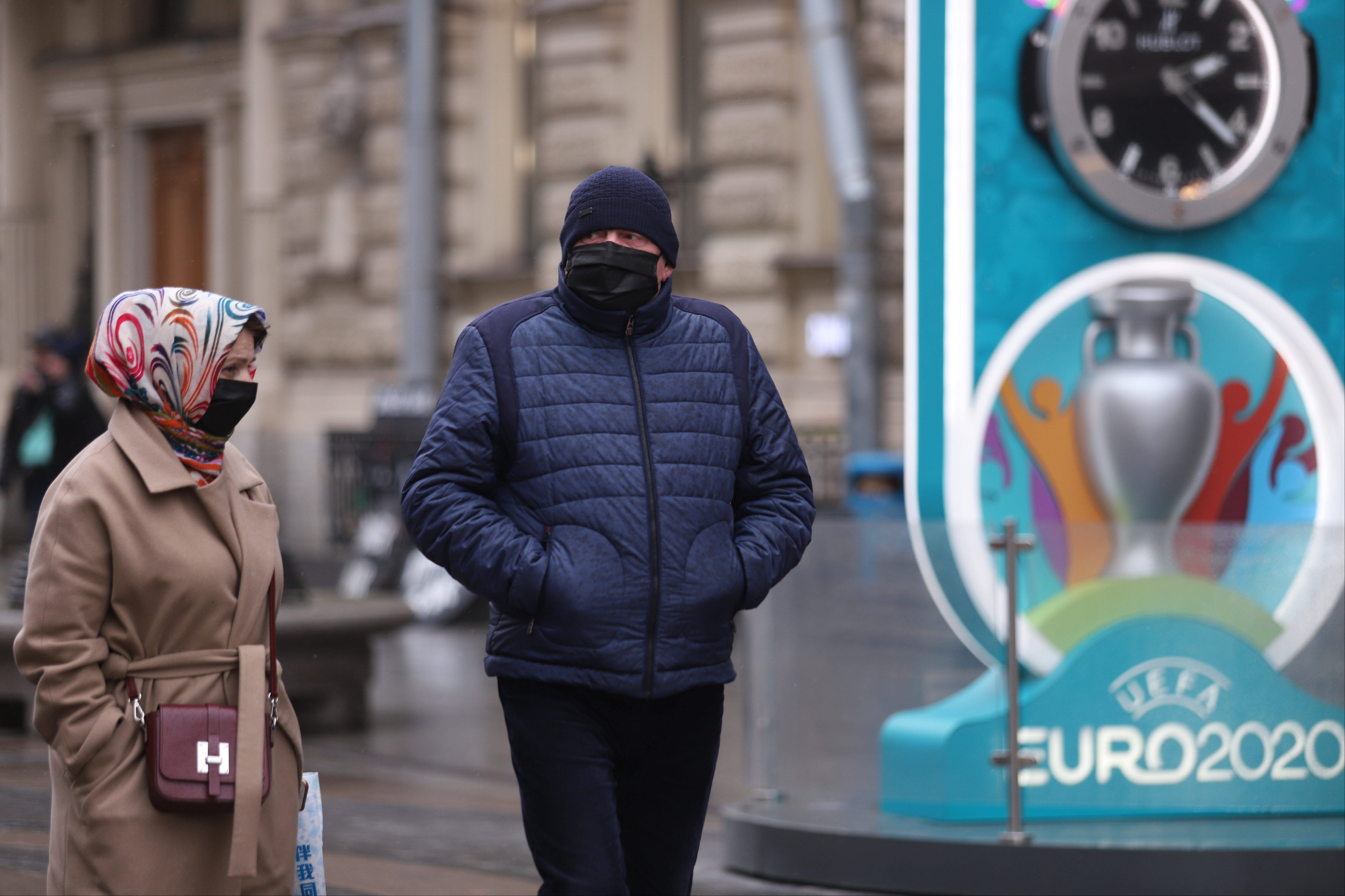 Menschen mit Mund-Nasen-Schutz an einem EM-Logo in Sankt Petersburg