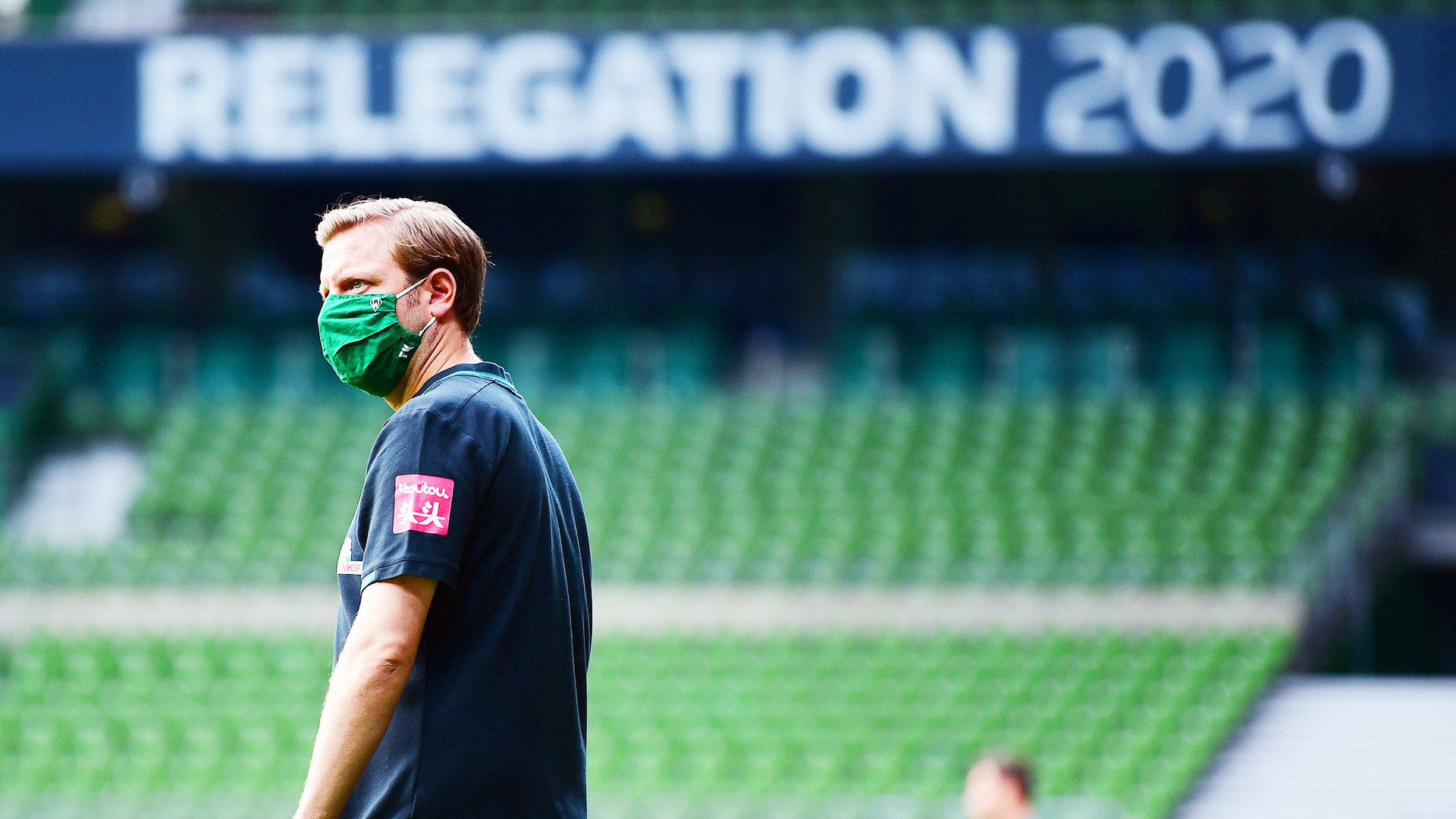 Werder Bremens Trainer Florian Kohfeldt vor einem großen Schild mit der Aufschrift "Relegation 2020".